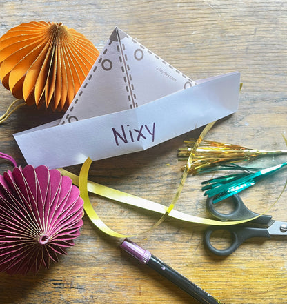 Safari hat with 'Nixy' name on a wooden surface with decorative items and scissors.